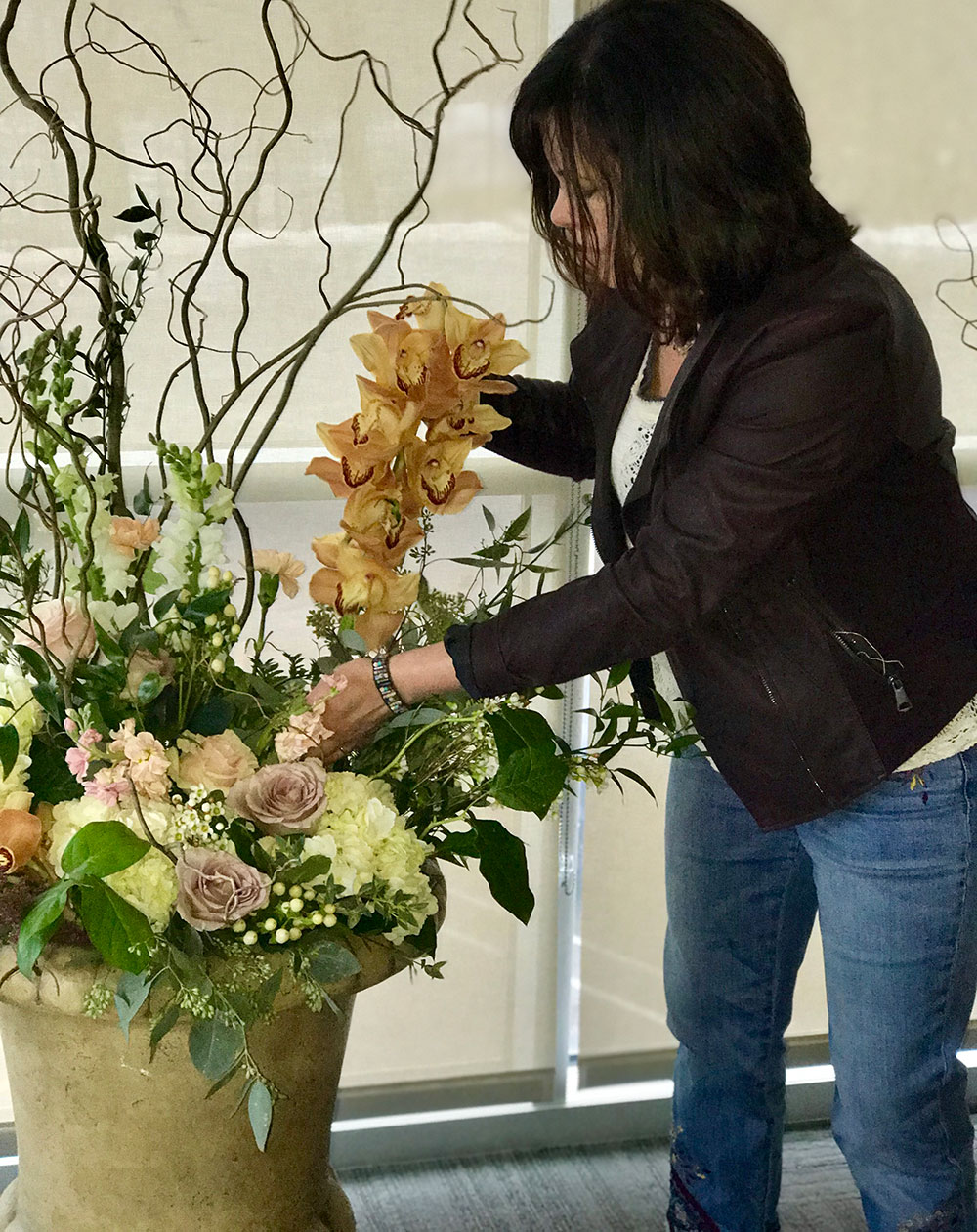 Image of owner, Tracey Flanigan arranging a large urn vase.