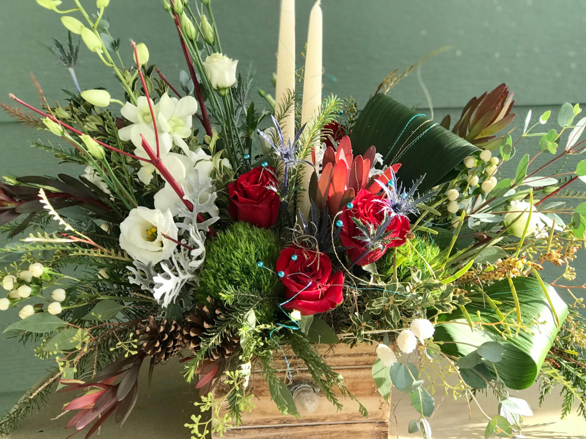 Holiday Centerpiece with roses, orchids and candles in a wooden container