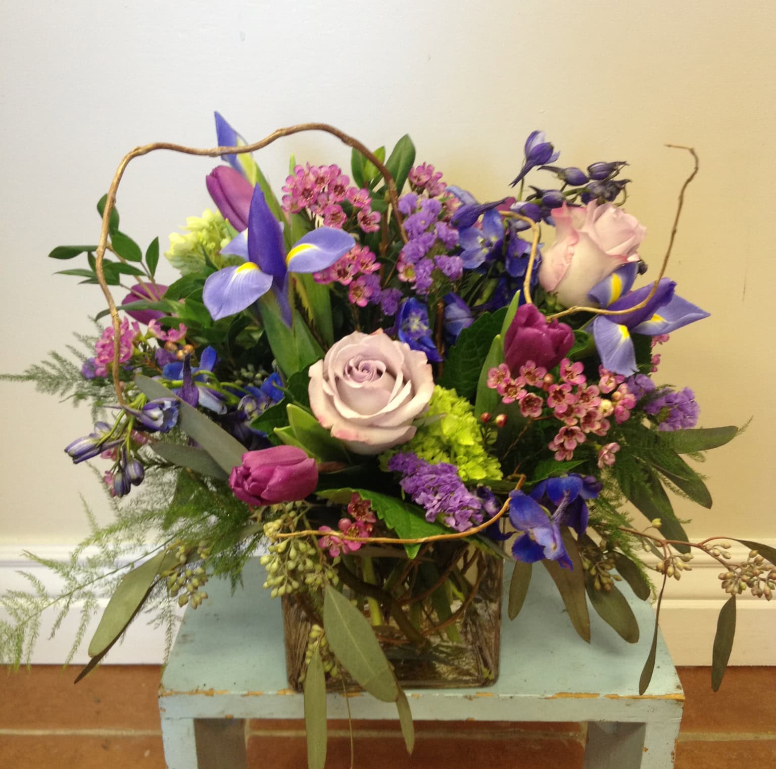An arrangement of deep purples, blues and pinks with curly willow from Art in Bloom Floral Studio in Howell, Michigan.